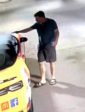The man beside the yellow vehicle with one hand extended to its rear.