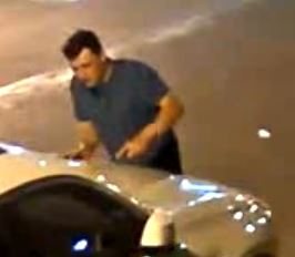 Close view of the man bending forward over the roof of a vehicle.
